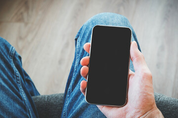 close up of male hand holding smartphone with black screen, space for your text, copy space, mock up