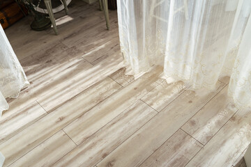 The flooring in a modern room with light pouring in through the curtains