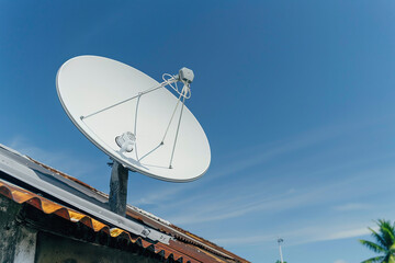 technology in poor community, contrast between dilapidated housing and new satellite dish being installed on rusty roof