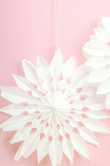 Traditional paper 3D snowflakes on pastel pink background. Winter handmade, DIY activity