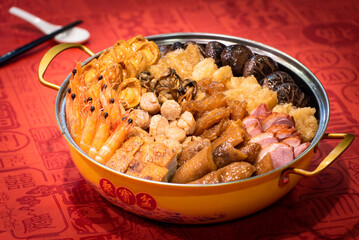 chinese traditional Peng cai with luxury seafood, meat, vegetable and premium sauce in hot pot in red chinese new year background asian halal menu