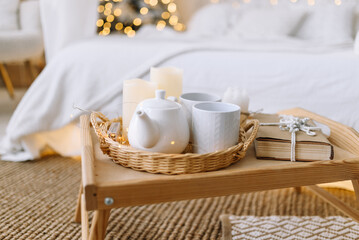 Holiday breakfast
A wooden tray with cups of tea, candles and gifts is placed on a cozy rug. The background is decorated with a Christmas tree, creating a festive fairy tale atmosphere.