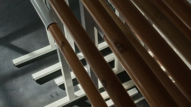 No people closeup view of ballet studio with wooden ballet barres mounted on sleek white metal support structure in soft natural light and shadows