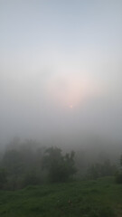 Naklejka premium A tranquil scene of a misty sky at dawn, with the landscape partially obscured by fog and the soft light of morning breaking through 