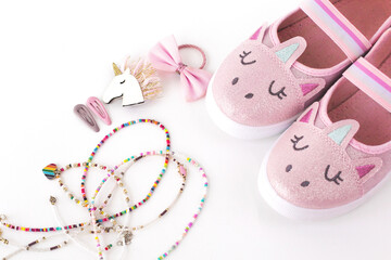 Children's beautiful stylish pink shiny shoes for girls and accessories pink and purple, hairpins, beads and jewelry on a white background
