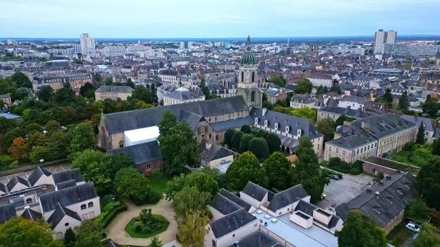 Notre-Dame-en-Saint-Melaine French abbey church over Thabor park. Rennes, Ille-et-Vilaine in Brittany, France. Aerial drone forward and cityscape