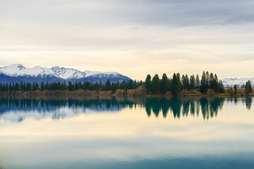A crystal-clear reflection of the turquoise waters of Lake Ruataniwha, framed by distant mountains and a clear sky. This iconic spot is a showcase of New Zealand's pristine natural beauty.