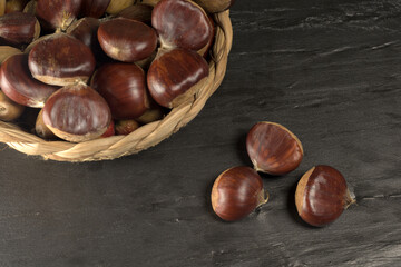 Chestnuts and autumn leaves on black background