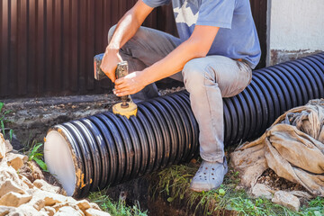 Obraz premium Installation of plastic black pipes for flow of rainwater to main a collector