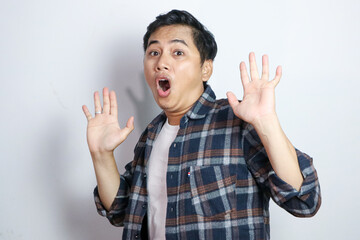 Excited Asian man gasping with hands open and looking to copy space isolated on white background