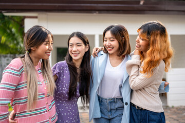 Group of women friends standing together outdoors in front of a house. 