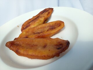 Fried banana isolated on white background. A dish made from banana fried with flour batter into a snack with a sweet and delicious taste. Food photography. Macro photography. Close up. Copy space.