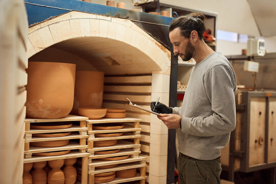 Ceramist doing an inventory of earthenware in a workshop kiln