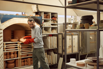 Ceramist removing clay plates from a workshop kiln