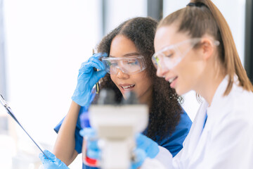 Two female scientists work in a laboratory with blood samples and test tubes filled with solution...