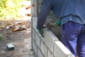 masonry worker make concrete wall by cement block and plaster at construction site