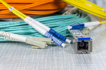 Close up side view of orange, yellow, cyan coloured optical cables coiled into a ring with...