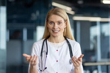 Smiling female doctor with stethoscope communicating on video call. Professional healthcare look,...