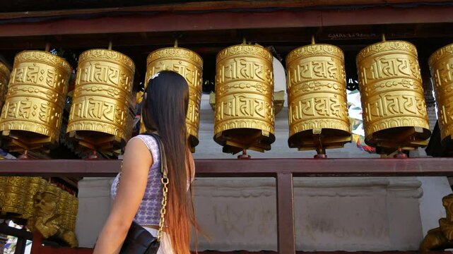 A girl spinning the golden prayer wheels from UNESCO world heritage site Swayambhunath Stupa a Buddhist temple in Kathmandu Nepal.