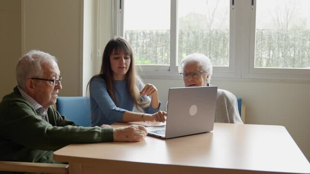 Nurse patiently teaches an elderly couple how to use a laptop, fostering digital literacy and connection