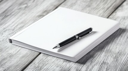 A simple white notebook and pen on a clean wooden desk, ready for note-taking.