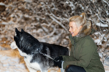 Beautiful girl of European appearance with a husky dog ​​in a winter forest, close-up photo.