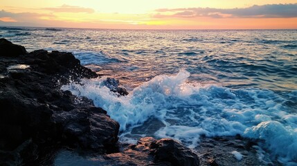 Fototapeta premium Blue waves gently crashing against a rocky shore at sunset, with the sky glowing in the distance.