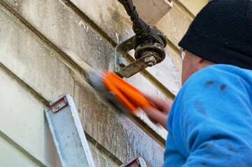 Scrubbing the house before painting, there is movement blur on the brush he is scrubbing so quickly