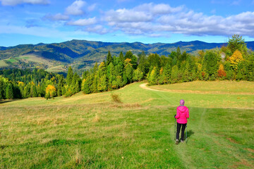 Scene in Pieniny mountains on a warm and sunny autumn day.
Woman backpacker on hiking trail in the mountains in autumn sunny day, against the backdrop of unreal views.
