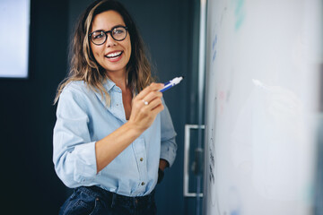 Happy business woman writing and presenting her ideas on a board during a business meeting