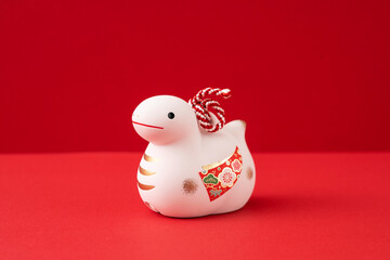 Japanese new year material. Zodiac Snake. Snake ornament on the red background. 日本のお正月素材。干支の巳（ヘビ）。赤背景上の巳の置物
