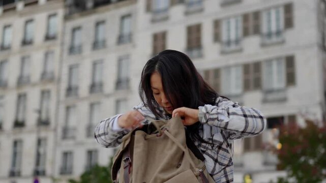 Chinese woman searching something in the backpack. She is in a hurry