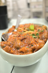 Spicy Indian mushroom with gravy served in white bowl in restaurant.