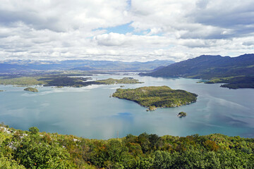 Aerial view of Slano Lake - a landmark in the vicinity of Niksic. Landscape taken during a trip to Montenegro: a large artificial lake with numerous islands, mountains and a beautiful cloudy sky