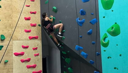 Teenage girl at indoor climbing wall. Kid having fun at bouldering wall. Child learning at climbing class. Sports healthy lifestyle. Youth at climbing summer camp