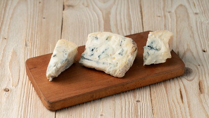 pieces of gorgonzola on a wooden cutting board, close-up, healthy food