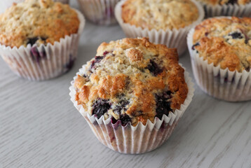Mixed berry muffins on a white wooden board.