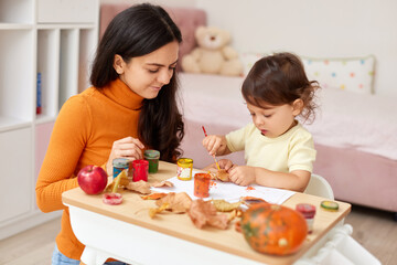happy little child girl and her mother drawing for the autumn holiday. Autumn craft