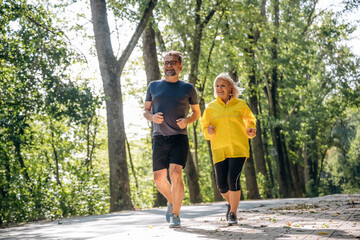 Fototapeta premium Front view, jogging, sports. Senior couple together outdoors at nature