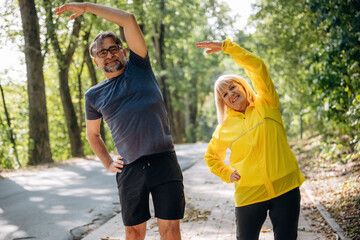 Obraz premium Warm up exercises, doing sport. Senior couple together outdoors at nature