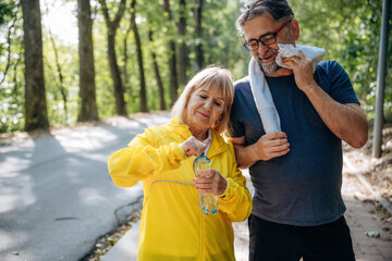 Fototapeta premium Stay hydrated. With bottle of water after jogging. Senior couple together outdoors at nature