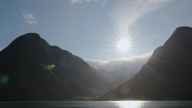 Pan over mountains at Sandvevatnet, blue skay and rain, sun flares