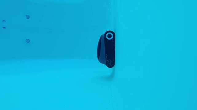 A robotic pool cleaner moves across the pool floor, automated technology to ensure efficient cleaning and maintenance in an underwater environment. 