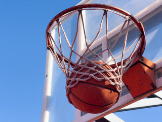 basketball drop into the orange metal goal and white net.