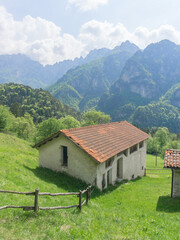 Serene mountain landscape with layers of misty hills in the background and lush green trees in the foreground with a cabin in the field, capturing the peaceful beauty of nature.