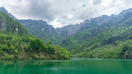 Natural lake on a cloudy day with big mountains surrounding it