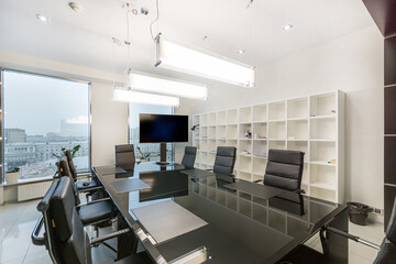 Spacious meeting room in a modern office. A long table, ergonomic chairs and a large TV.
