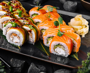 Sushi rolls set served on black stone plate with wasabi and ginger