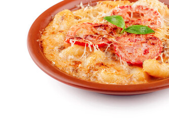 Gnocchi with melted cheese, tomato and basil is served on a plate