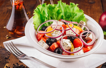 Greek salad with feta cheese, vegetables and olives on rustic wooden table background